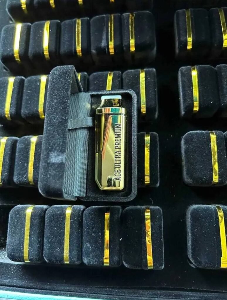 Gold ACE Ultra Premium vape device displayed inside a black velvet case, surrounded by similar devices.